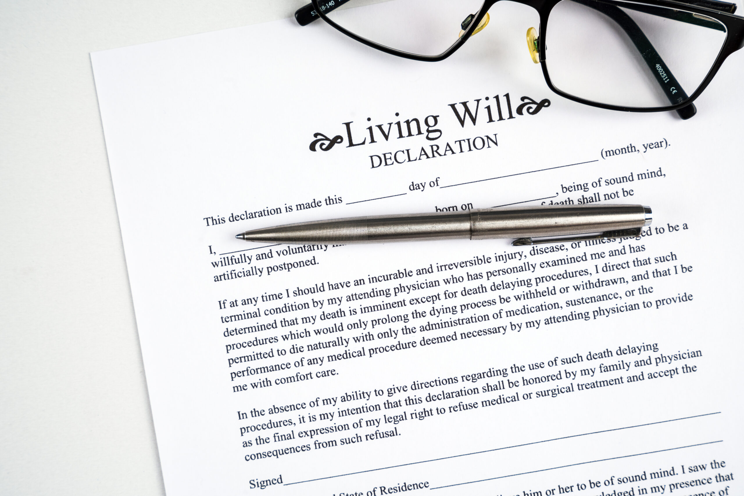 Living will declaration form with glasses and silver pen.