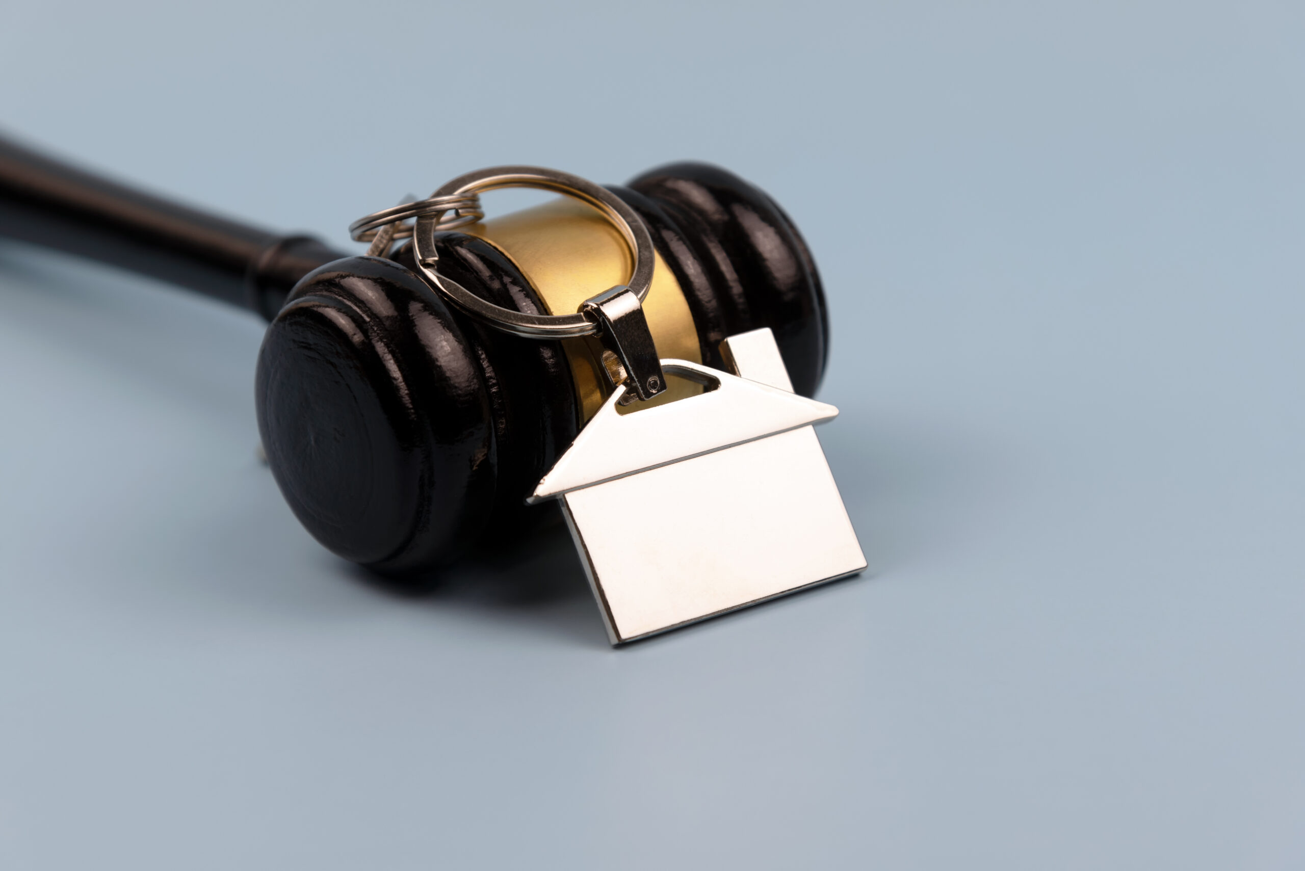 Gavel and model house blue background